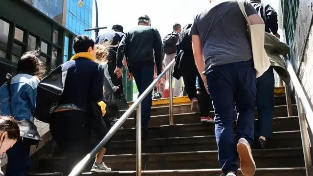 Pessoas sobem escada em direção à rua, em local público